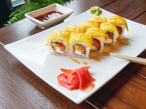 Rolls with rice, seaweed nori, salmon, cream cheese, chicken egg, caviar masago, orange. Marinated ginger and wasabi sauce. Asian cuisine, traditional dish - sushi.