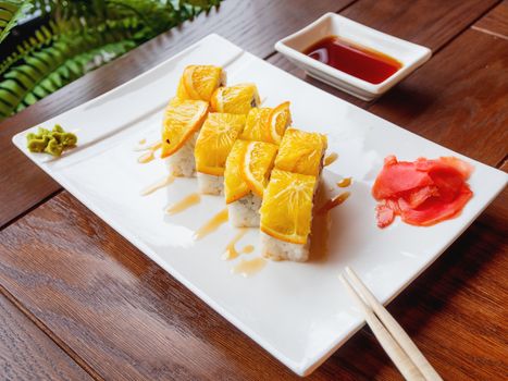 Rolls with rice, seaweed nori, salmon, cream cheese, chicken egg, caviar masago, orange. Marinated ginger and wasabi sauce. Asian cuisine, traditional dish - sushi.