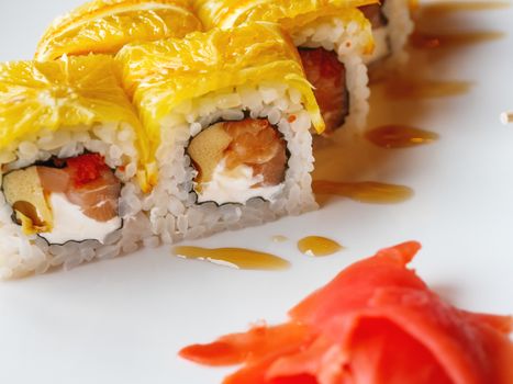 Rolls with rice, seaweed nori, salmon, cream cheese, chicken egg, caviar masago, orange. Marinated ginger and wasabi sauce. Asian cuisine, traditional dish - sushi.