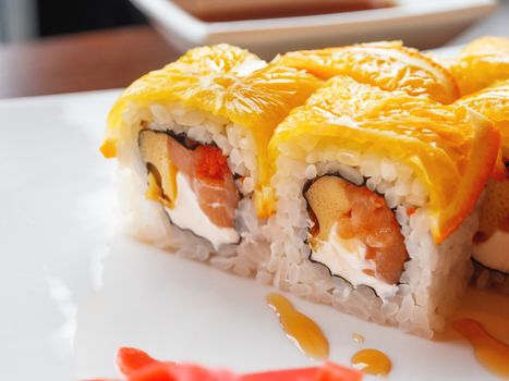 Rolls with rice, seaweed nori, salmon, cream cheese, chicken egg, caviar masago, orange. Marinated ginger and wasabi sauce. Asian cuisine, traditional dish - sushi.