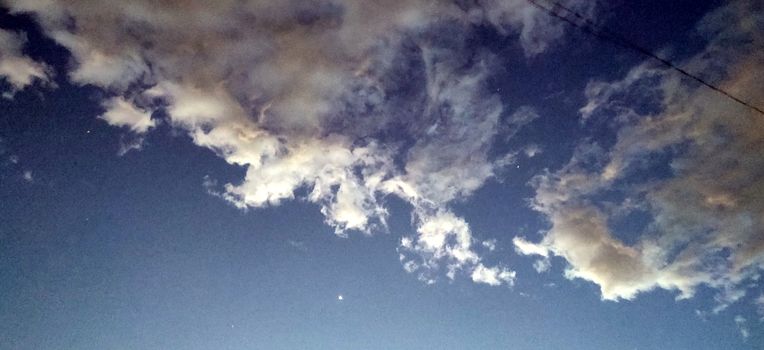 The twilight blue sky and the reddish clouds with stars shining and a wire in foreground