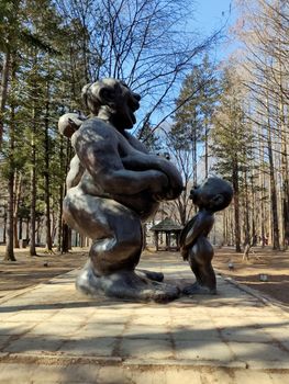 A famous statue of a naked mother breast feeding her naked child with one more child hanging off her back in Nami Island in South Korea.