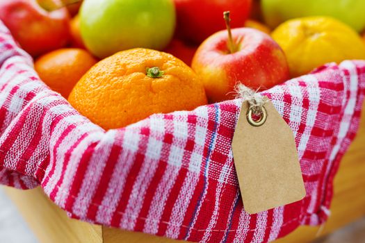 Box full of fresh fruits. Fruit harvest - apples, oranges, lemon. Clear tag for your text.