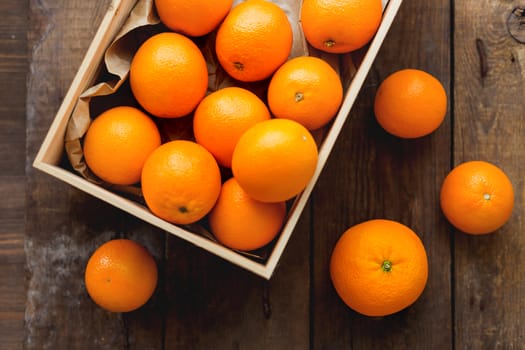 Box full of fresh oranges. Fruit harvest on old rustic wooden background.