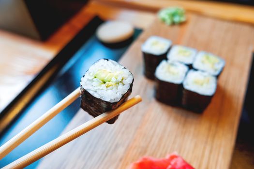 Rolls in nori seaweed with avocado, pickled ginger and soy sauce. Asian cuisine, traditional dish - sushi.