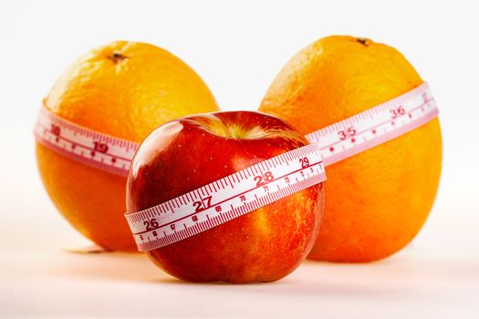 Oranges and apple with tailor's ruler. Fruit healhy vitamin diet helps to lose weight.