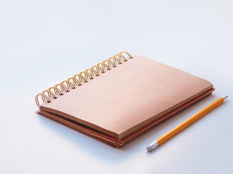 Notepad with craft paper pages and orange pencil. Copy space.