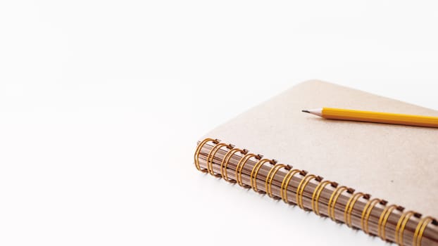 Notepad with craft paper pages and orange pencil. Banner with copy space.