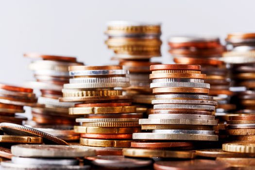 Big heap of columns of different coins on white background. May be used as symbol of increase in wealth.