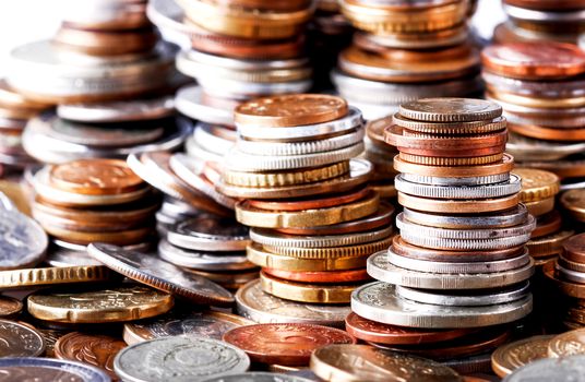 Big heap of columns of different coins on white background. May be used as symbol of increase in wealth.