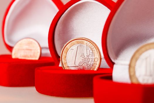 Red gift boxes with one euro, ten roubles and one cent coins. Focus on euro coin, the official currency of the eurozone (European Union).