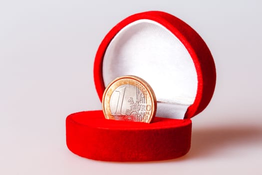 Red gift box with one euro coin, the official currency of the eurozone (European Union).
