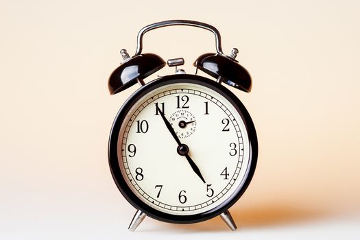 Black old fashioned alarm clock on beige background.