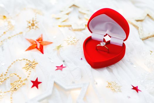 Christmas and New Year holiday background with decorations and engagement golden ring with diamond in gift heart box. Valentine's Day card.