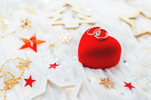 Christmas and New Year holiday background with decorations and wedding rings on gift heart box.