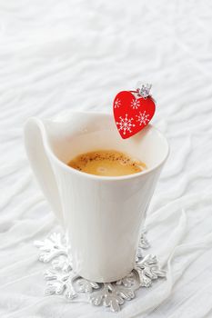 White cup of hot coffee with decorative heart and engagement diamond ring, symbol of love and marriage. Valentine's day background with place for text.