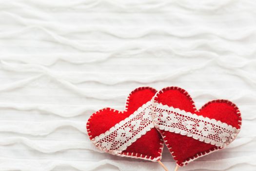 White fabric background with ruche.Two felt hearts with laces, symbol of love. Good for Valentine's Day cards. Place for text.