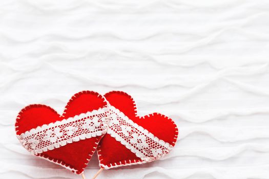 White fabric background with ruche.Two felt hearts with laces, symbol of love. Good for Valentine's Day cards. Place for text.