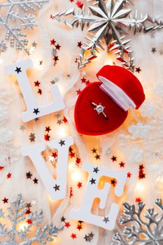 Christmas, New Year and Valentine's Day background with engagement ring, light bulbs and decorations. Symbol of love and marriage.