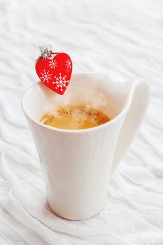 White cup of hot coffee with decorative heart and engagement diamond ring, symbol of love and marriage. Valentine's day background with place for text.