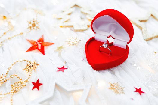 Christmas and New Year holiday background with decorations and engagement golden ring with diamond in gift heart box. Valentine's Day card.