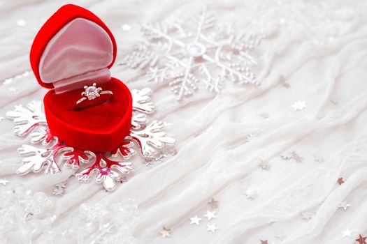 Engagement diamond ring in red gift box on white fabric background. Good for Valentine's day cards. Place for text.