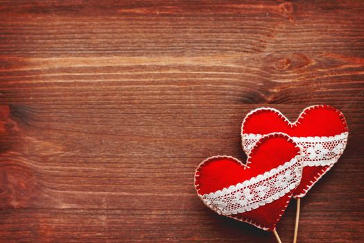 Two felt hearts with laces, symbol of love, on wooden background. Good for Valentine's Day cards. Place for text.