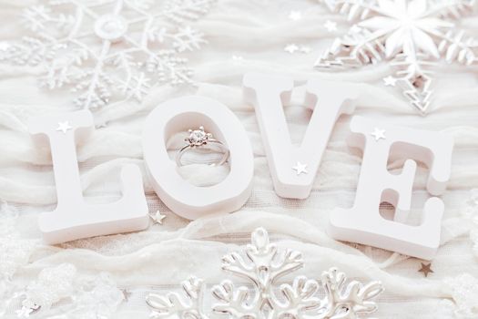 Word LOVE on white fabric background with engagement diamond ring. Good for Valentine's day cards.