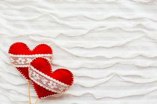 White fabric background with ruche.Two felt hearts with laces, symbol of love. Good for Valentine's Day cards. Place for text.