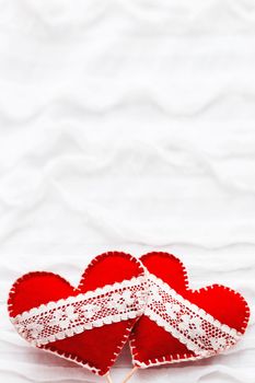 White fabric background with ruche.Two felt hearts with laces, symbol of love. Good for Valentine's Day cards. Place for text.