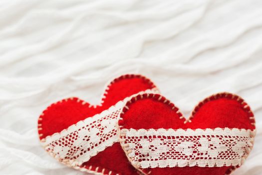 White fabric background with ruche.Two felt hearts with laces, symbol of love. Good for Valentine's Day cards. Place for text.