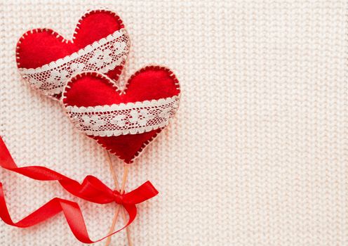 White woven background with two felt hearts with laces, symbol of love. Good for Valentine's Day cards. Place for text.