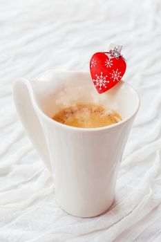 White cup of hot coffee with decorative heart and engagement diamond ring, symbol of love and marriage. Valentine's day background with place for text.