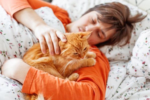 Man and ginger cat in bed. Cute cozy home background. Morning bedtime.