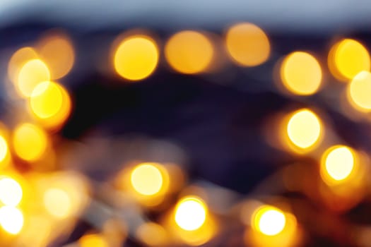 Defocused night street lights, blurred colorful bokeh background. Holiday colorful lanterns and light bulbs garlands.