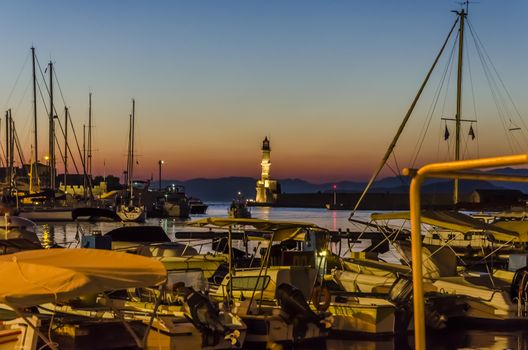 Boats lighthouse and evening in a port of Crete.