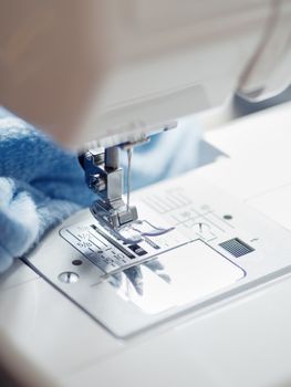 Close up of sewing machine. Blue fabric on background. Equipment for hand made things, hobby.