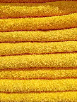 Stack of yellow terry towels. Pile of textile bath accessories.