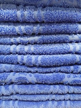 Stack of blue terry towels. Pile of textile bath accessories.