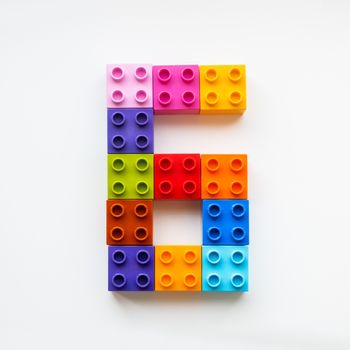 Number Six made of colorful constructor blocks. Toy bricks lying in order, making number 6. Education process - learning numbers with child using multicolored toy details.