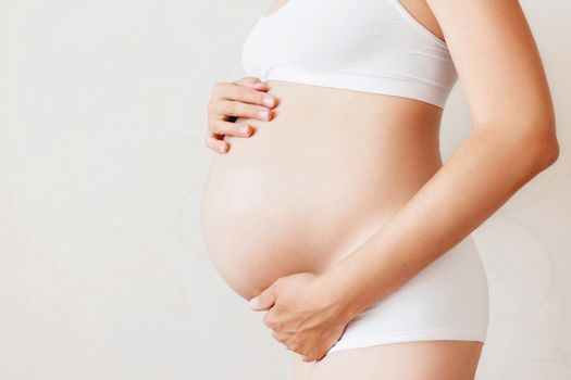 Pregnant woman in white underwear. Young woman expecting a baby.