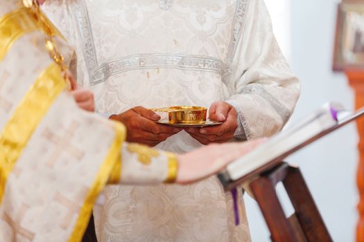 Wedding ceremony in orthodox Church. Priest is holding a golden cup of wine. Details of ritual. Russia.