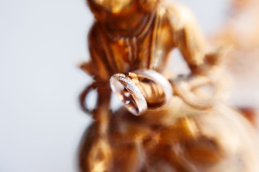 Pair of wedding rings with diamonds on unknown goddess statue. Old rusty metal sculpture captured with Lens Baby Sweet 35mm.