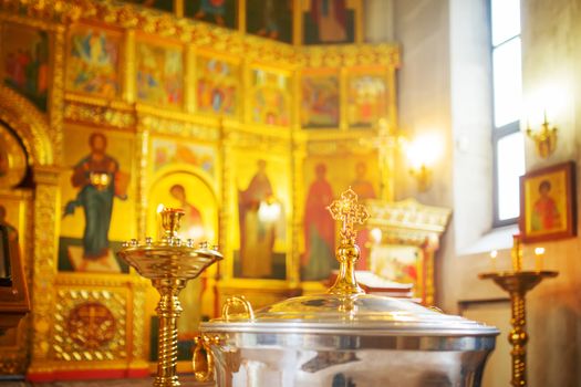 The font for the baptism of children in the Orthodox Church. Symbolic Orthodox gold cross on the cover font.
