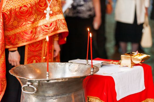 The font with candles for the christening of children in the Orthodox Church.