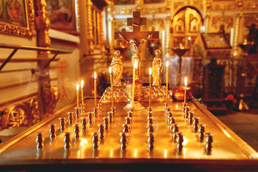 Golden candleholder in Orthodox church. Symbolic Orthodox gold cross with the crucifixion of Jesus.