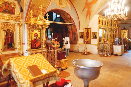 Interior of Orthodox church. Symbolic Orthodox gold cross with the crucifixion of Jesus, golden candleholders and other details.