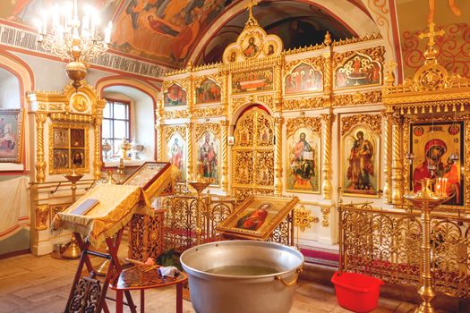 Golden religious utensils - Bible, cross, prayer book, missal, baptismal font. Interoior of Orthodox Christian Church. Russia.