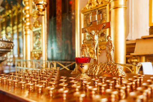 Golden candleholder in Orthodox church. Symbolic Orthodox gold cross with the crucifixion of Jesus.