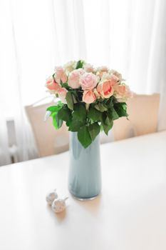 Bouquet of peach colored roses in light blue vase on table.
